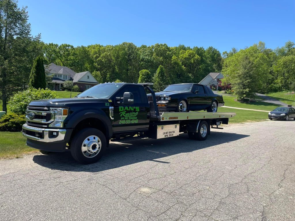 A tow truck transporting a black car on its flatbed, showcasing the towing process in action.